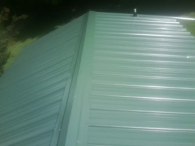 New green metal panels meeting at the ridge of a roof — Flat Roof Repair work by our crew in Wilbur