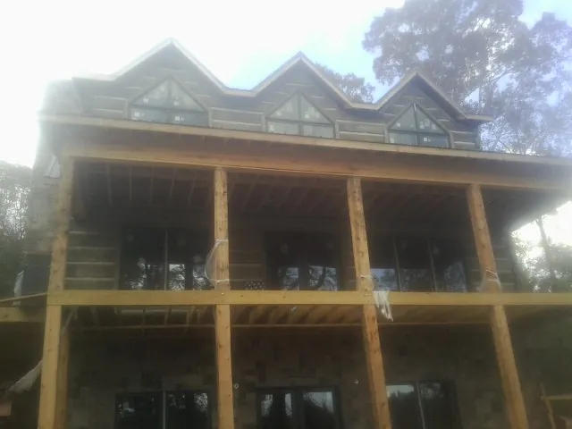 Dormers and porch framing on a large log home under construction — Roof Coating work by our crew in Wilbur