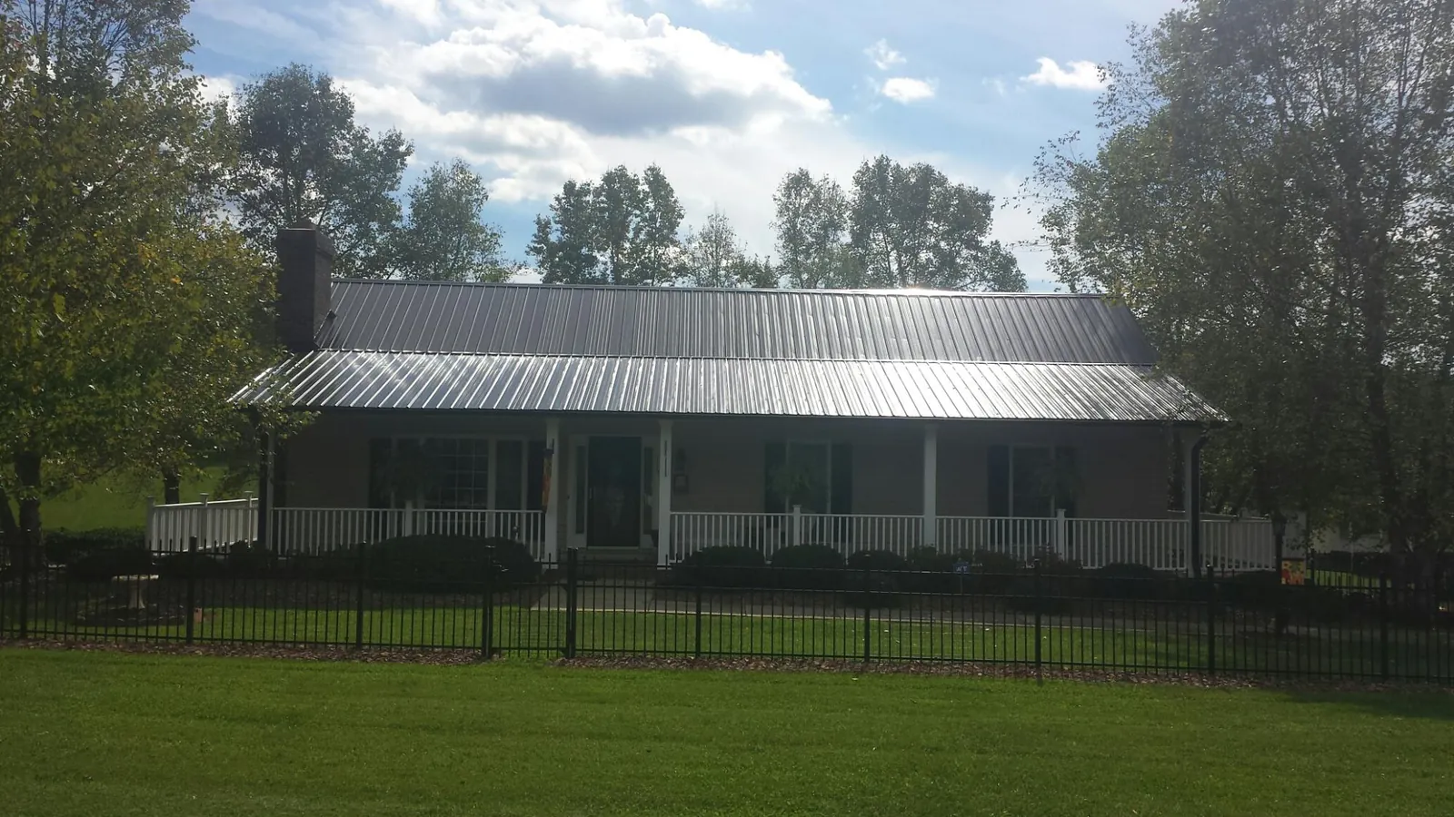 Gray metal roof on a brick ranch with a full width front porch — Gutter Guard Installation work by our crew in Wilbur