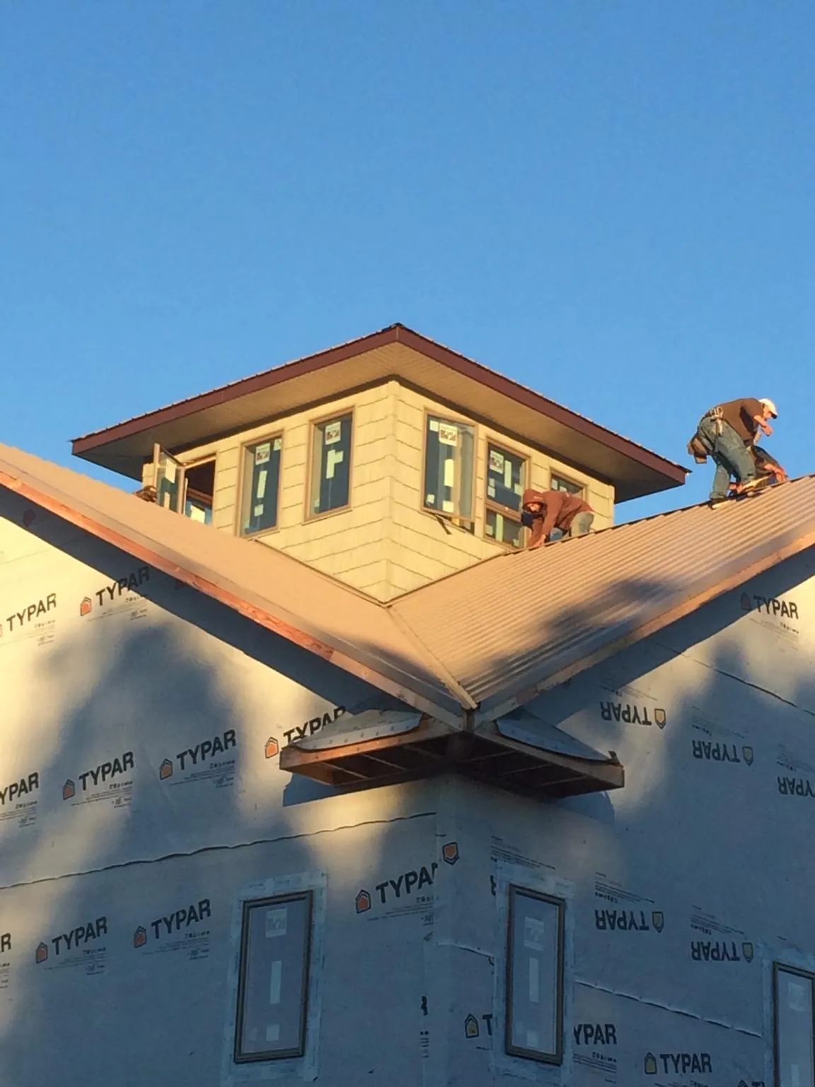 Roofers working around a rooftop cupola on a new metal roof at sunset — Roof Waterproofing in Wilbur by Roofing Brothers